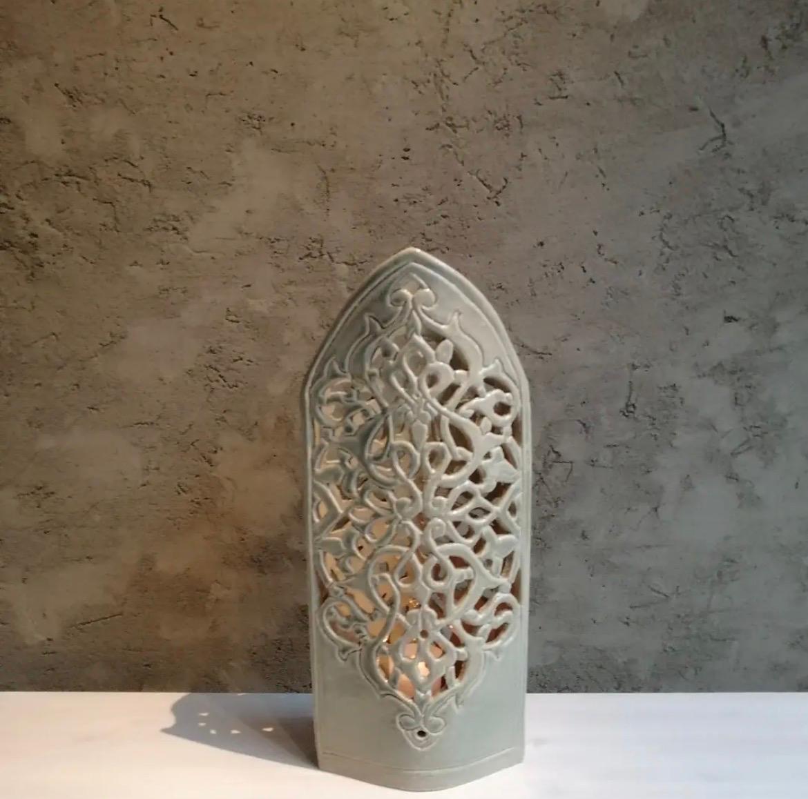 Tall white pierced ceramic form with a pointed silhouette and repeating openwork