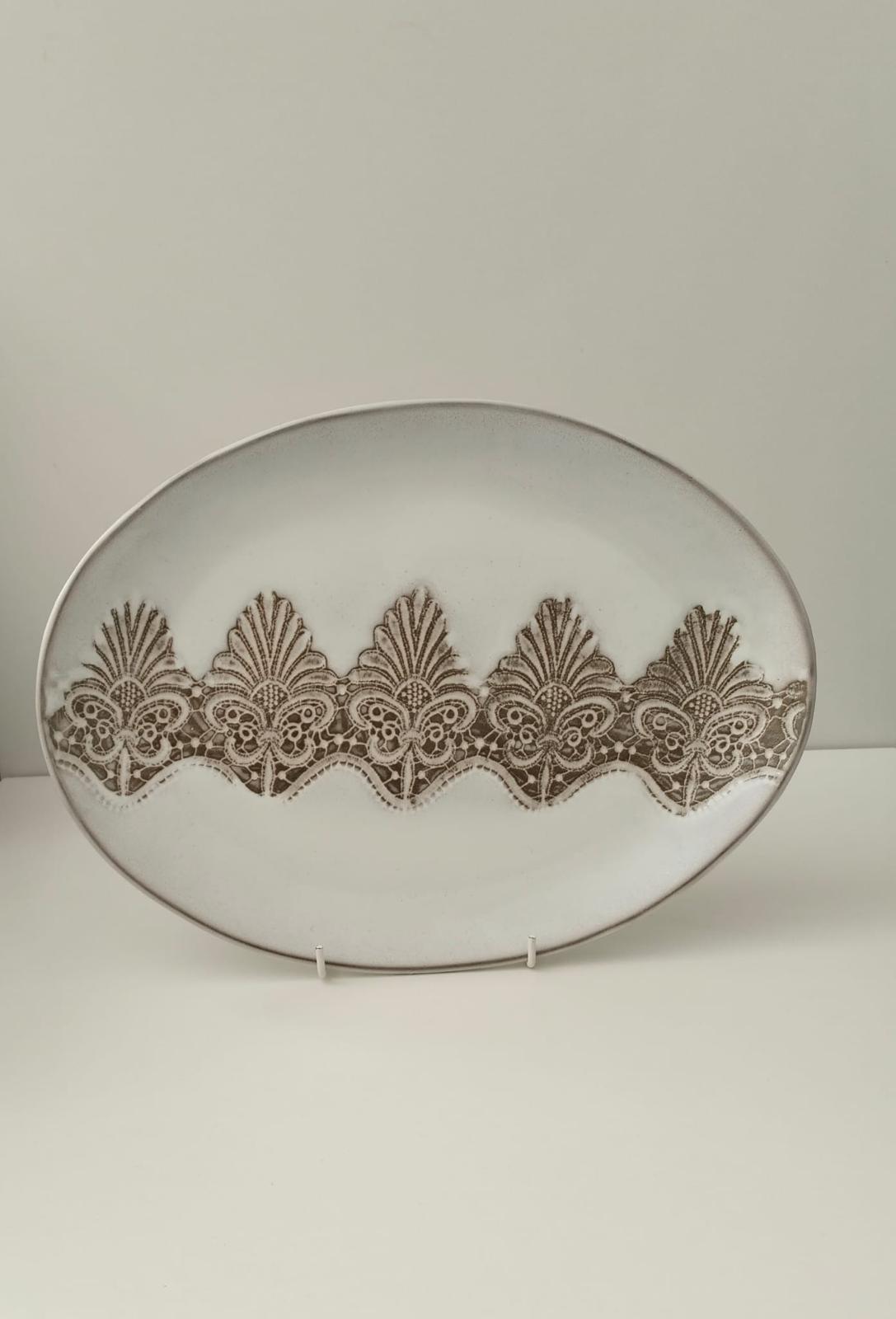 Oval ceramic platter covered with a repeating ornamental relief pattern