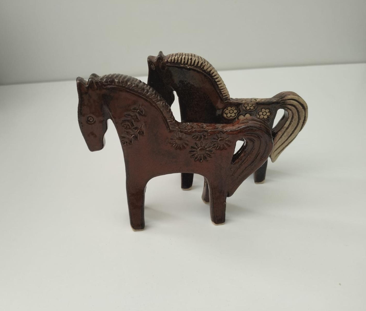 Two ceramic horse sculptures with carved and impressed surface patterns