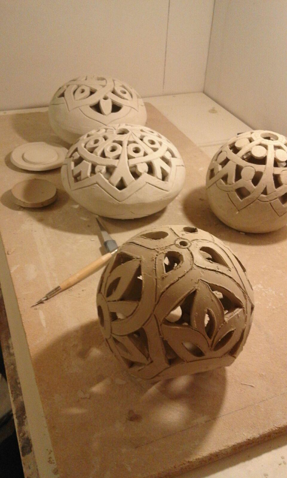 Unfinished raw clay pierced spherical forms on the worktable in Raed's studio